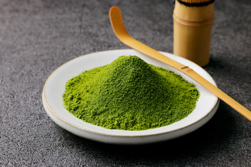 グレーのモダンな背景に映える鮮やかな日本の抹茶の粉末　Premium authentic Japanese matcha powder on a minimalist grey texture background