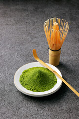 グレーのモダンな背景に映える鮮やかな日本の抹茶の粉末　Premium authentic Japanese matcha powder on a minimalist grey texture background