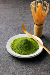 グレーのモダンな背景に映える鮮やかな日本の抹茶の粉末　Premium authentic Japanese matcha powder on a minimalist grey texture background