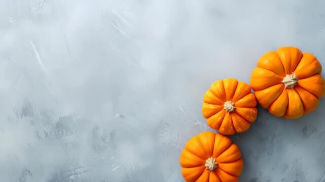 Orange mini pumpkins and autumn leaves on gray surface. Fall season concept for thanksgiving or halloween decoration.