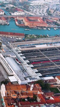4K aerial vertical video of Venice Santa Lucia Train Station. Aerial view of railway tracks, high-speed trains, and Grand Canal. Vertical video for Italy travel reels.