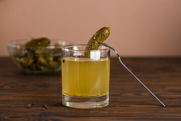 Homemade cucumber juice or pickle drink with cucumbers on the wooden table. Pickled vegetables preserved, canned greens, marinated greens, pickled cucumber.