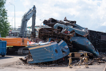 The dented, mangled bodies of subway passenger cars sit in an open-air dump next to an excavator.