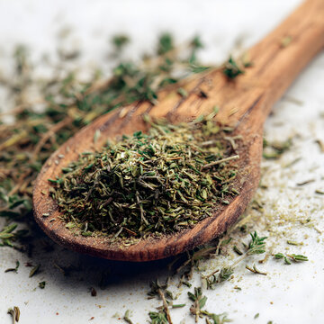 Wooden spoon with dried herbs on a white surface thyme