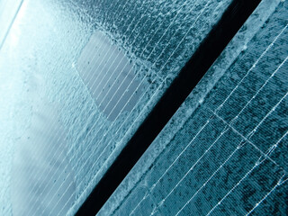 Extreme close-up of ice and frost patterns on a blue solar panel in winter.