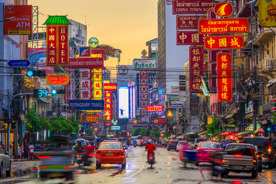 BANGKOK, THAILAND - SEPTEMBER 27, 2015: Traffic on Yaowarat Road passes below lit signs in the Chinatown district at dusk.
