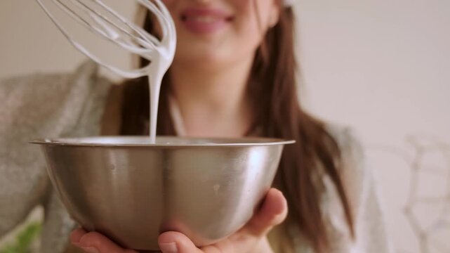  Smiling woman in cozy home clothes gently whipping glaze for Easter cake enjoying magic of holiday baking