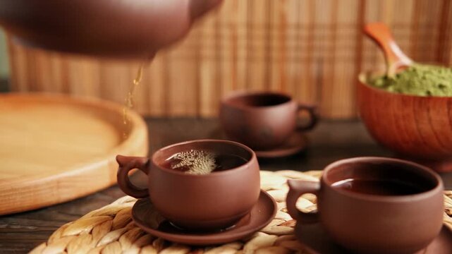 ea Ceremony. Traditional Asian Tea Utensil, Serving Authentic Set. Person Pouring Tea from Brown Pottery Teapot to Teacup. Bamboo Tray. Lifestyle. Wellness Balance Health. Tea Brewing Equipment