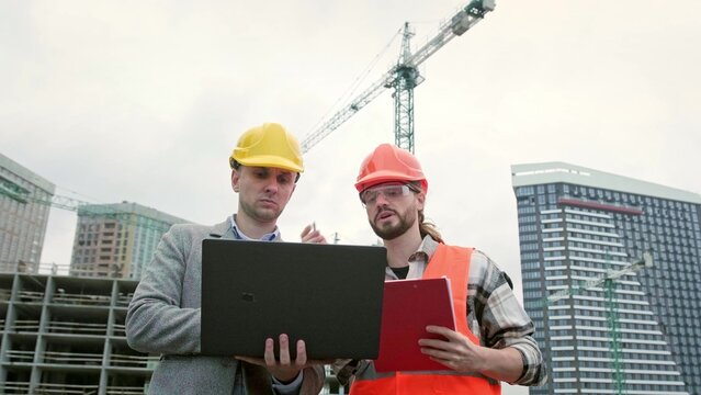 General contractor and subcontractor using laptop during site inspection