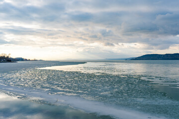 Fototapeta premium Frozen lake with dramatic cloudy winter sky on Lake Balaton in Hungary