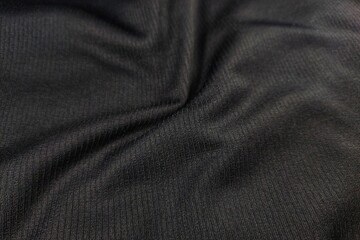 Perspective view of dark black ribbed fabric texture background macro
