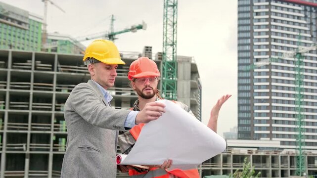 Team of building experts with drawings inspecting new development site