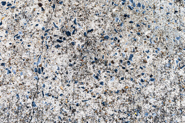 Detail of aggregate concrete floor showing embedded blue and grey crushed stones with a natural vertical surface crack. © Thanawin