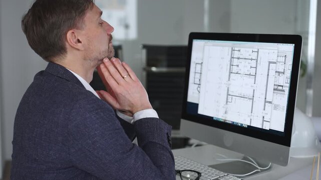 Businessman stressing at his office desk, covering face with hands. Feeling tired, having a headache from work overload. Business and architecture concept