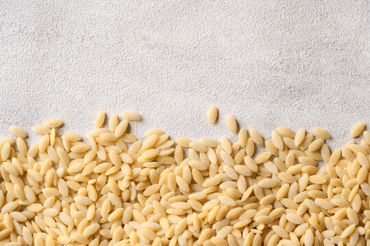 flat lay pile of risoni or rice shape pasta on table white food background with copy space