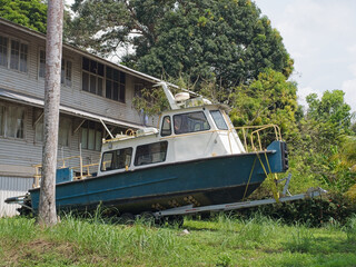 Obraz premium Green and white tourist boat on trailer beside wooden tropical pier building with palm trees