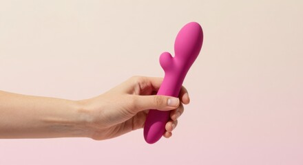 Elegant hand holding a vibrant pink personal massager against a soft pastel background, highlighting sensual wellness and intimate lifestyle choices for self-care and relaxation