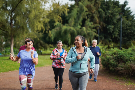Group of multiracial senior friends running at city park - Fit elderly people having fun doing sport endurance workout together outdoor