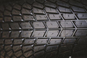 Obraz premium Detailed macro shot of a new black motorcycle tire, showing the symmetrical tread pattern and small rubber vent spews. High-quality rubber surface for maximum grip.