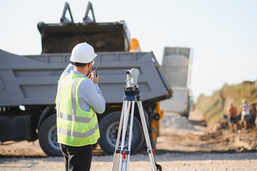 Surveyor using total station at road construction site