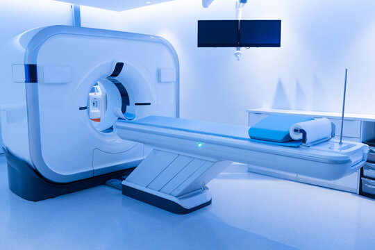 Medical tomography gantry sitting in radiology room, showing motorized table with blue head cushion