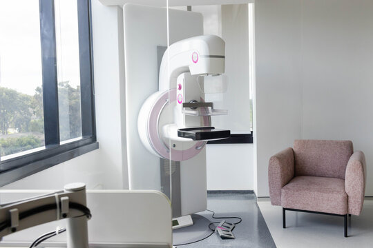Mammography machine featuring compression plate and detector tray standing in exam room near window