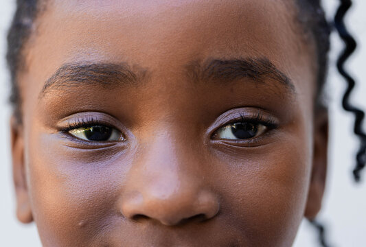 Youth African female gazing into camera at portrait set, showing lavender eyeshadow and braid