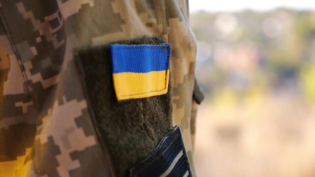 Close up of military blue-yellow chevron on shoulder of soldier at countryside. This emblem embodies the unbreakable spirit and pride of the ukrainian people. Concept of invasion resistance