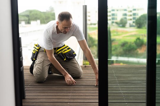 Deck or terrace construction, builder hand installing impregnated wooden boards