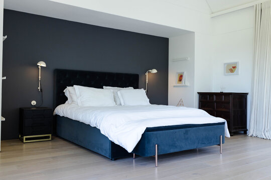 Large dark blue velvet bed is sitting in modern bedroom with white duvet and tufted headboard