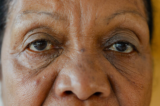 Senior African American woman gazing directly into camera in room, showing detailed skin texture