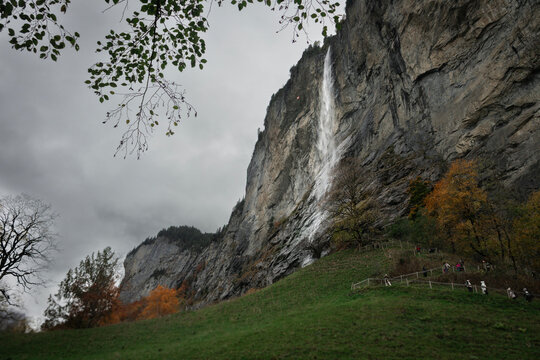 Cachoeira impressionante de Staubbachfall caindo livremente de uma altura de 297 metros pela face rochosa vertical do Vale de Lauterbrunnen, na Su&iacute;&ccedil;a. Enquadrada por folhas verdes e outonais em tons d