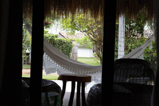 piscina de resort de luxo tropical &agrave; beira-mar (ou beachfront), com &aacute;guas azuis cristalinas, cercada por um gramado verde bem cuidado e dezenas de coqueiros altos (cocos nucifera) balan&ccedil;ando ao vento.