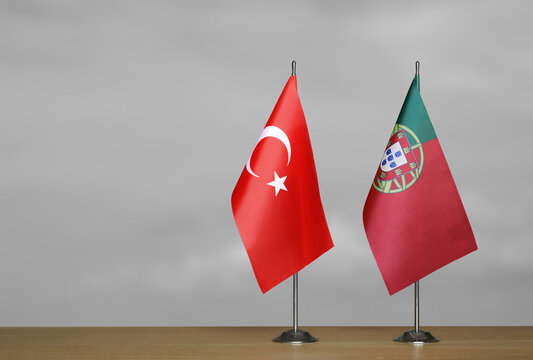 Two table flags of the Turkey and Portugal on a blurred gray background