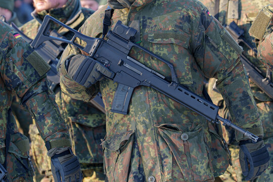 Close-up of a German soldier in flecktarn camouflage uniform holding a G36 assault rifle.