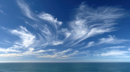 Obraz premium Azure Tapestry: High-altitude cirrus clouds paint an ethereal picture against a vast expanse of blue, above the calm sea, an awe-inspiring symphony of nature's beauty and wonder.