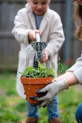 Child and adult watering potted plant together in backyard