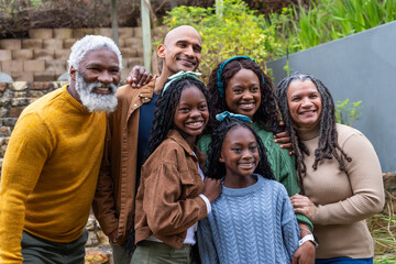 Obraz premium Diverse multi-generational family standing on stone steps by retaining wall, wearing knit sweaters