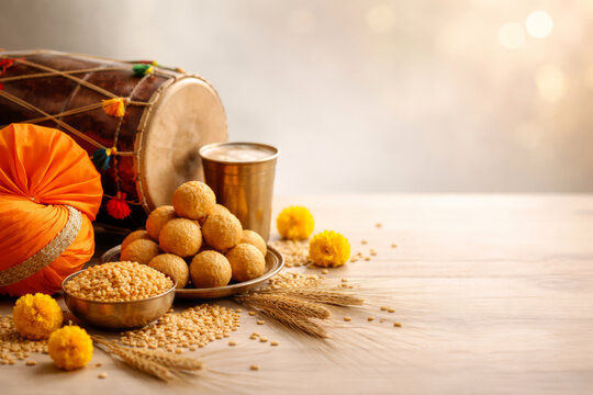 Baisakhi festival still life with Punjabi turban, dhol drum, ladoo sweets and wheat on light background with copy space.