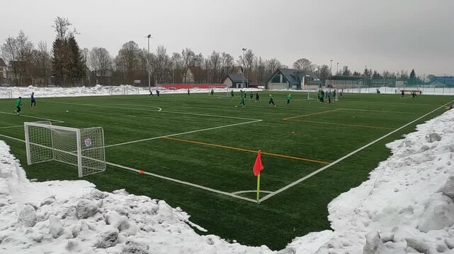 KRAKOW, POLAND - FEBRUARY 10, 2026: Children play soccer on the field in winter. Huge mounds of snow have been swept to the sides of the artificial lawn.