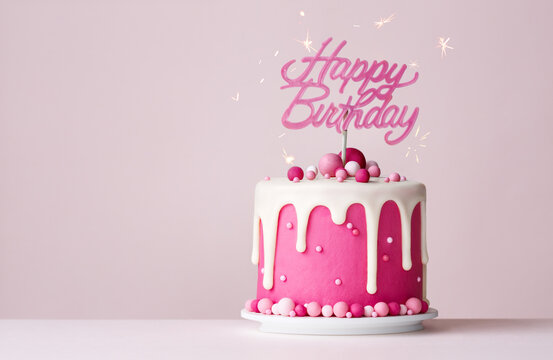 Pink celebration birthday cake with happy birthday banner and drip icing