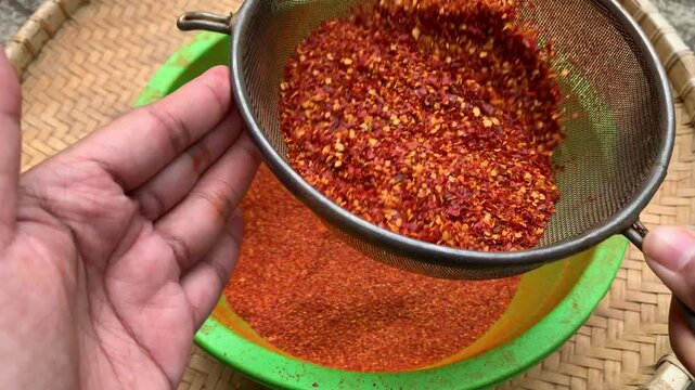 sifting dried hot peppers with strainer traditionally.
