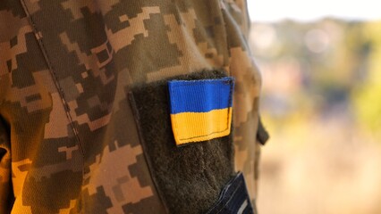 Close up of military blue-yellow chevron on shoulder of soldier at countryside. This emblem embodies the unbreakable spirit and pride of the ukrainian people. Concept of invasion resistance