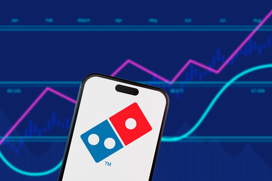 Brooklyn.New York.USA-02.13.2026: Domino's logo on a smartphone screen with financial growth charts. Concept for fast food industry stocks and retail restaurant trading