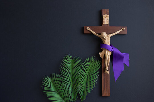 Crucifix with purple sash and palm leaves on black