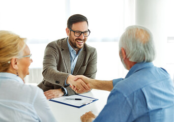 Portrait of a businessman or real estate agent or doctor shaking hands and signing a deal contract...