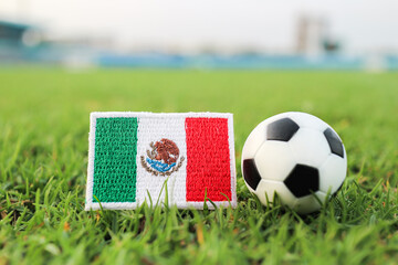 Mexican flag embroidered patch placed beside a soccer ball on green grass field. Concept of national pride, international football competition and Mexico sports identity promotion. © The Dell Shot by SJ