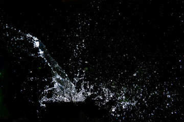 Splashing water with a dark backdrop, creating a dynamic and refreshing effect. The droplets scatter in various directions