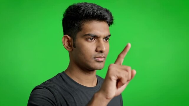 Person gesturing in front of bright green screen with focused expression