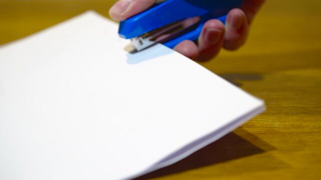 Close-up of office stapler binding sheets of paper with loud metallic click sound, stationery ASMR